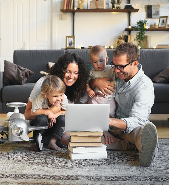 family sitting down on floor looking at computer